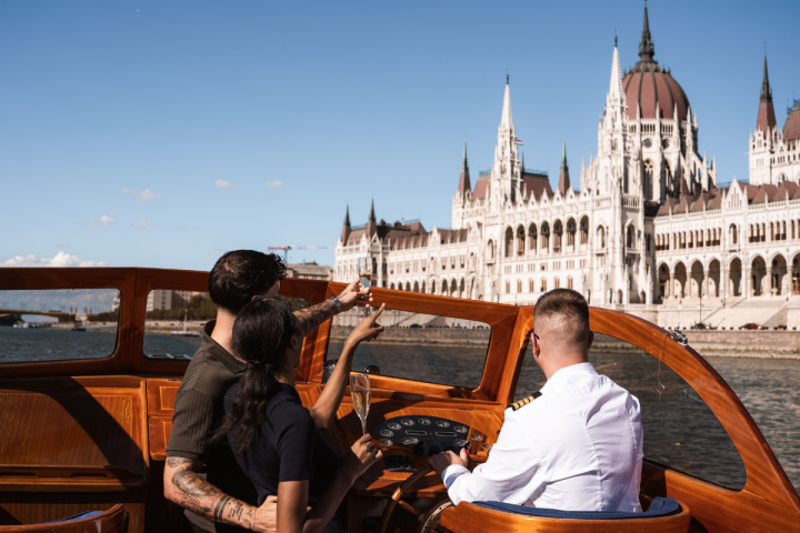 Three people on a boat near a large, ornate building by the water.