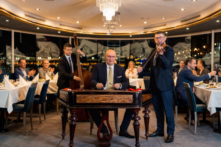 Musicians perform in a restaurant with guests dining and clapping, creating an elegant and lively atmosphere.