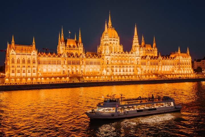 Illuminated building at night with a boat on the water in front.