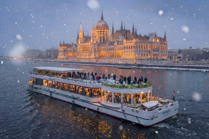 River cruise boat on the Danube with snowy Budapest Parliament building in the background.