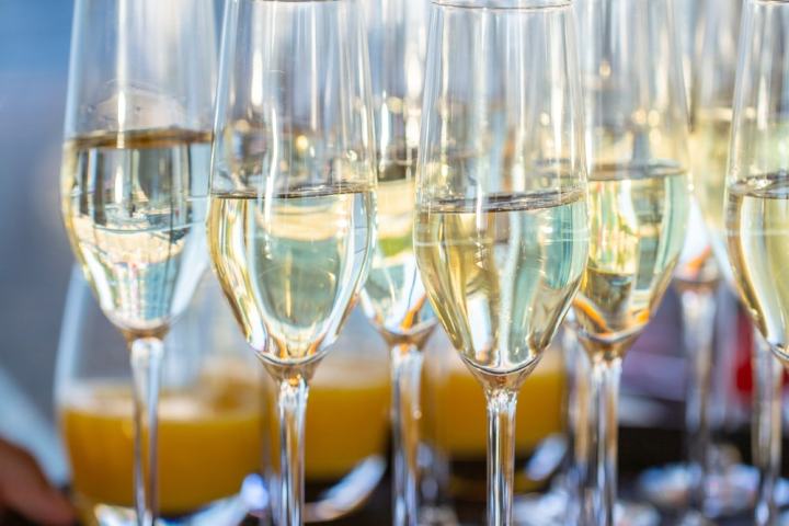 Close-up of several champagne glasses being carried on a tray by a hand.