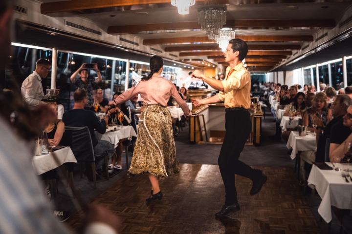 Two dancers performing in a crowded restaurant with diners watching.
